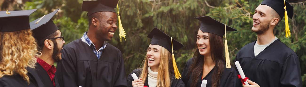 People wearing graduation gowns and mortarboards talking outdoors
